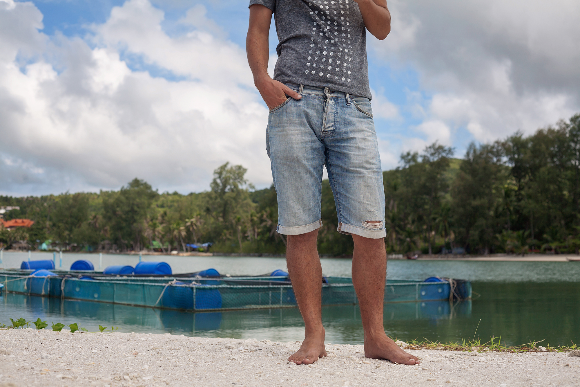 close up of young adult man in denim shorts.